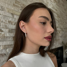 Woman wearing a pair of lab grown diamond hoop earrings set in white gold. 