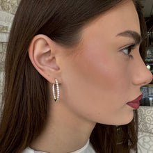 Woman wearing a pair of lab grown diamond hoop earrings set in white gold. 